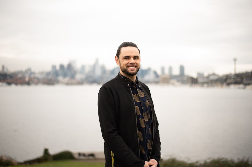 Devin Barich smiling in front of the Seattle, Washington skyline