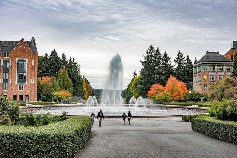Students walking on the University of Washington campus near a fountain