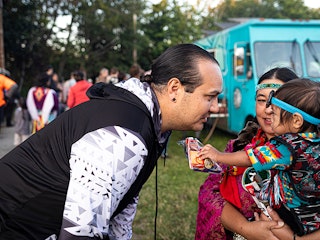 Iisaaksiichaa greets his sister and nephew at the powwow at Daybreak Star Cultural Center in Seattle.
