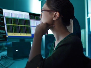 A data scientist analyzing information on computer monitors.