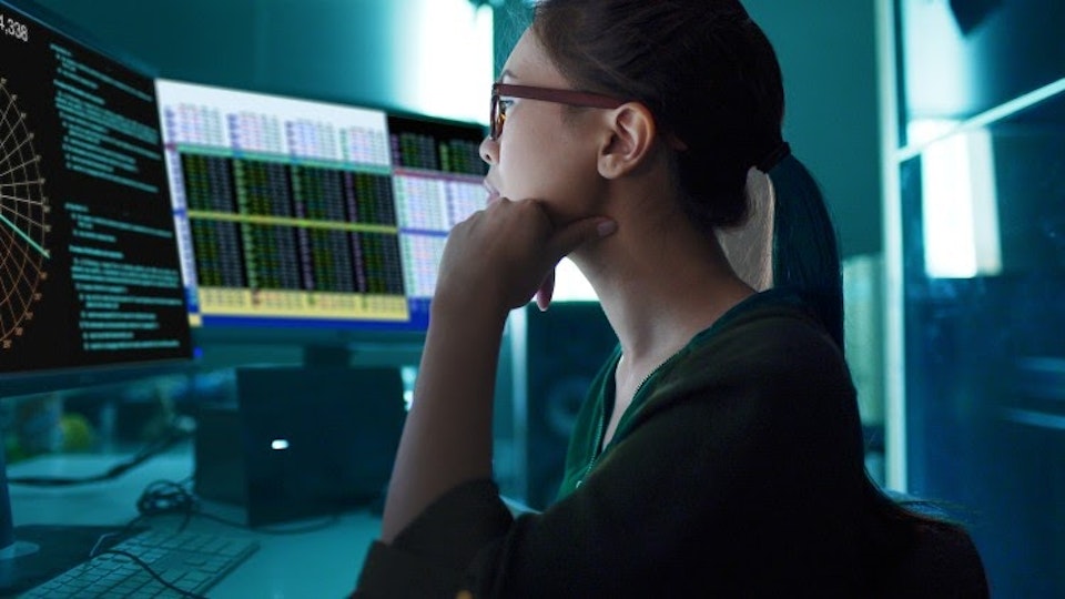 A data scientist analyzing information on computer monitors.